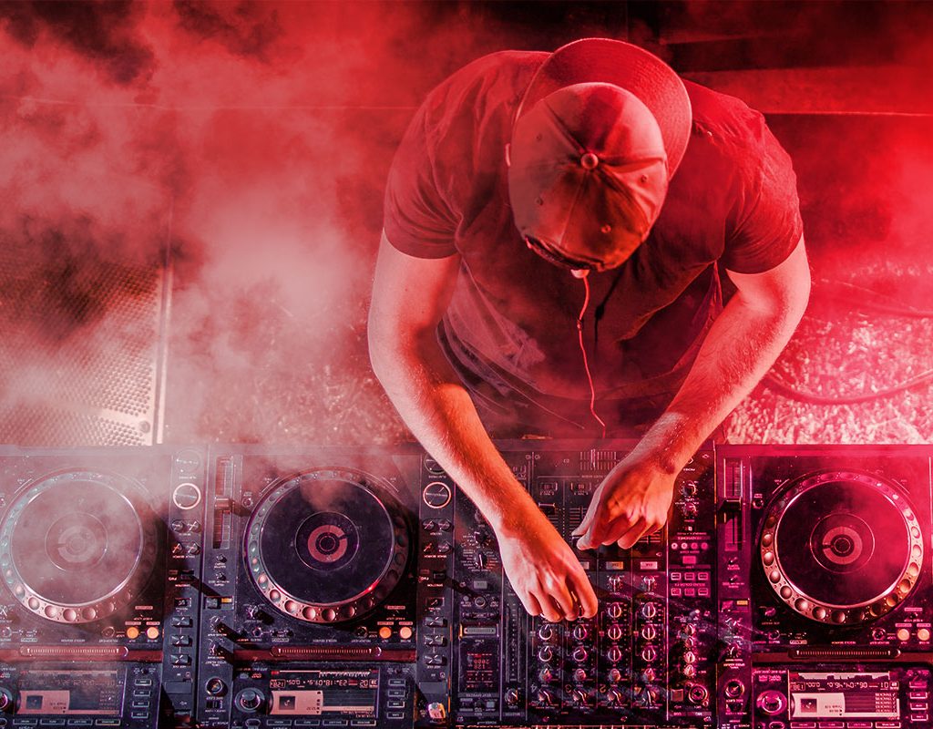 DJ performing on professional Pioneer decks under red stage lighting